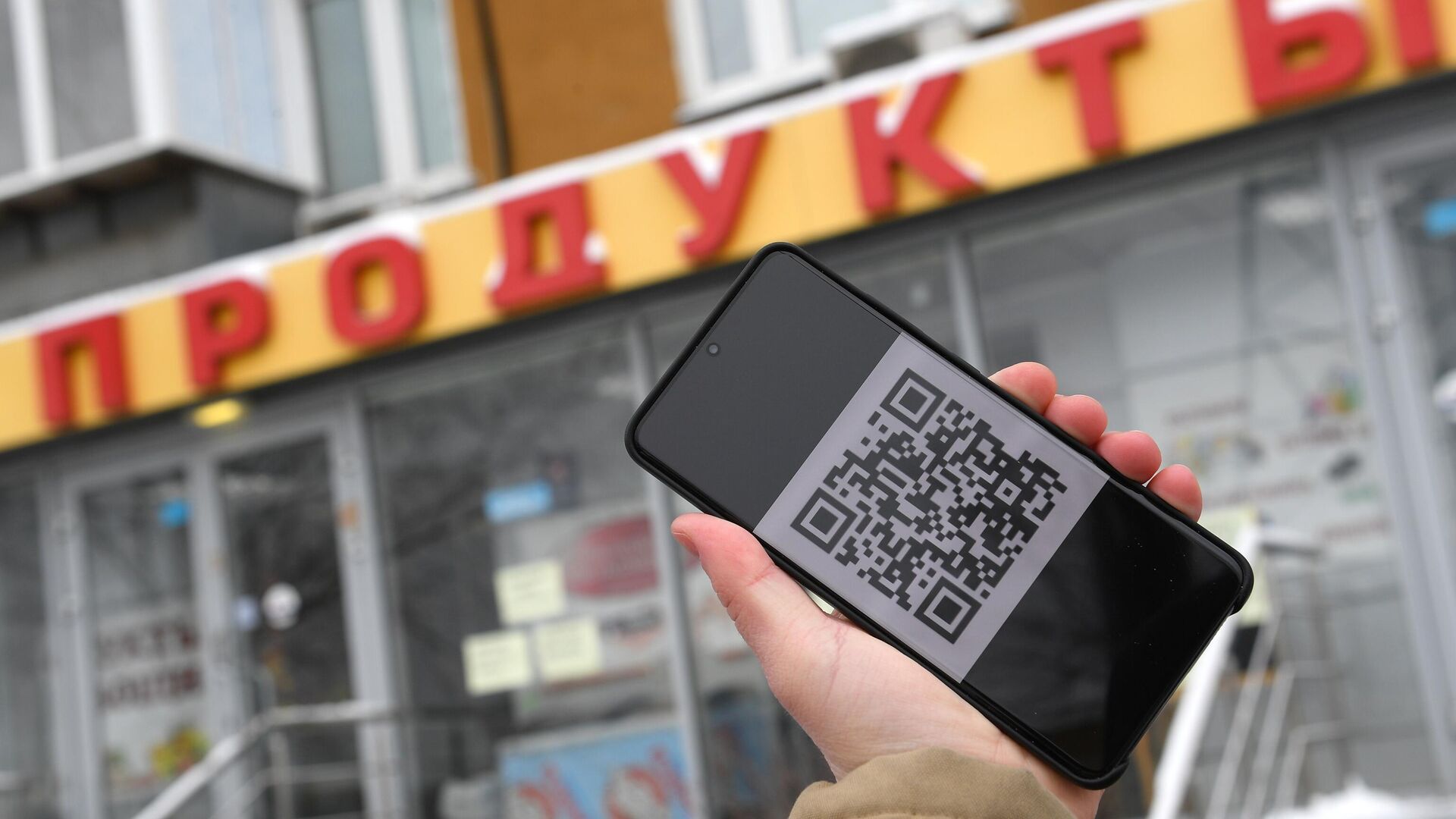 Человек держит смартфон с изображением QR-кода - РИА Новости, 1920, 11.11.2021