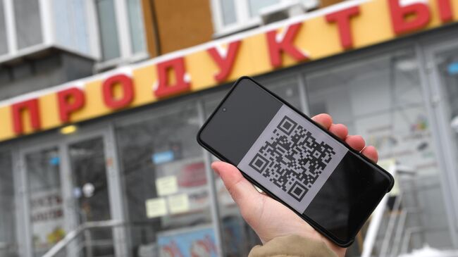 Человек держит смартфон с изображением QR-кода