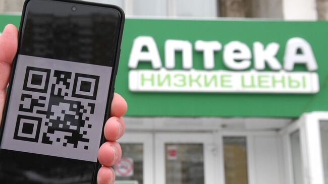 Человек держит смартфон с изображением QR-кода