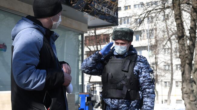 Сотрудник Росгвардии во время раздачи горожанам памяток по профилактике коронавирусной инфекции на одной из улиц в Москве