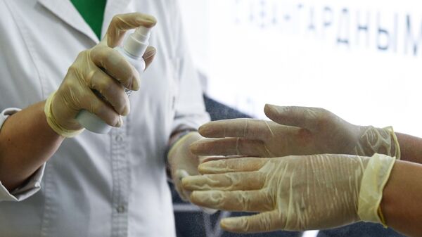 Медработники дезинфицируют свои руки в аэропорту Толмачево в Новосибирске