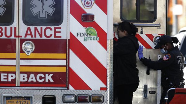 Сотрудница неотложной медицинской помощи Департамента пожарной охраны Нью-Йорка помогает пациентке сесть в машину скорой помощи