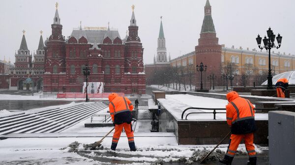 Сотрудники коммунальной службы убирают снег на Манежной площади в Москве