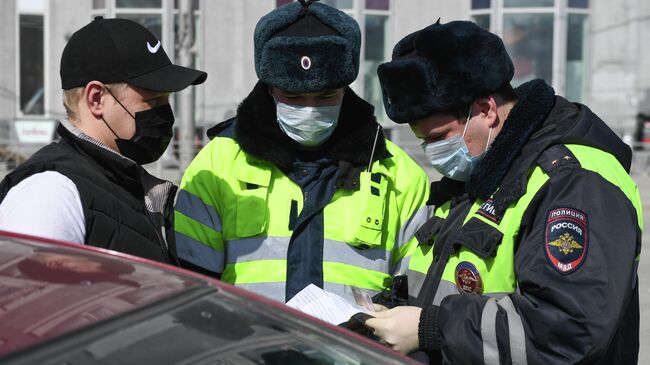 Сотрудники ГИБДД проверяют документы у водителя в рамках профилактических работ по защите населения от распространения коронавирусной инфекции