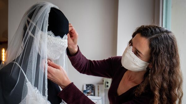 Дизайнер свадебного платья и вечерней одежды надевает защитную маску на манекен в своем магазине Chiton в Берлине 