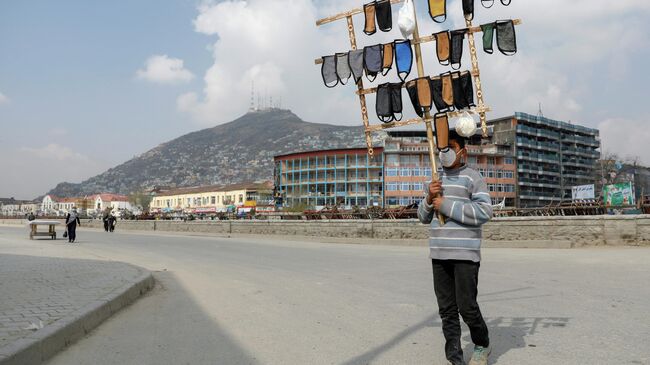 Афганский мальчик продает защитные маски в Кабуле