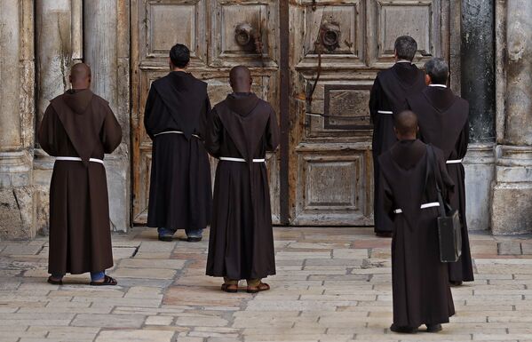 Францисканские монахи молятся перед закрытой дверью храма Гроба Господня в христианском квартале Старого города Иерусалима