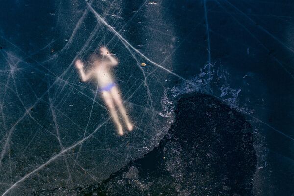Финский Фридайвер Kristian Maki-Jussila плавает подо льдом замерзшего озера близ Ваасы, Финляндия