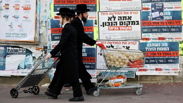 Ультраортодоксальные евреи проходят мимо информационных щитов, призывающих людей оставаться дома из-за пандемии коронавируса в Ашдоде, Израиль