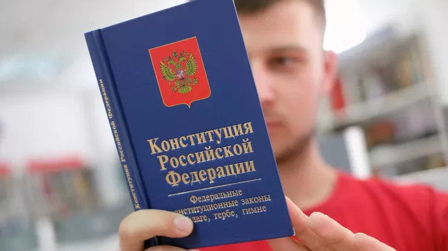 Молодой человек держит книгу конституции Российской Федерации