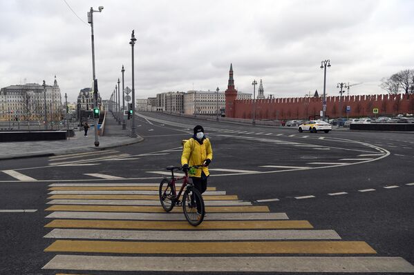 Сотрудник службы доставки Яндекс-Еда на пешеходном переходе улицы Варварка во время режима самоизоляции жителей