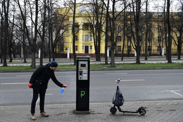 Мужчина дезинфицирует паркомат на улице в Москве