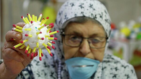 Пожилая женщина держит модель клетки коронавируса