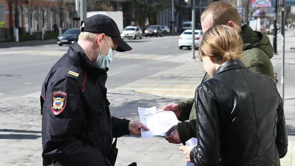 Сотрудник полиции проверяет документы у прохожих во время патрулирования улиц в Ростове-на-Дону