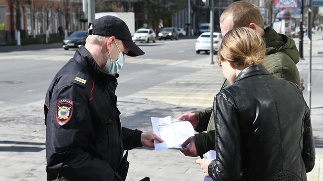 Сотрудник полиции проверяет документы у прохожих во время патрулирования