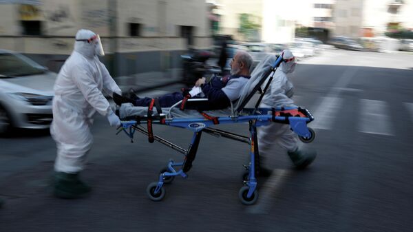 Медики в защитных костюмах перевозят пациента по улице в Неаполе