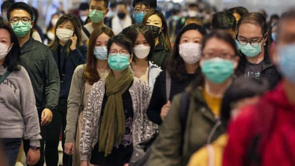 Пассажиры в медицинских масках в переходе метро Гонконга