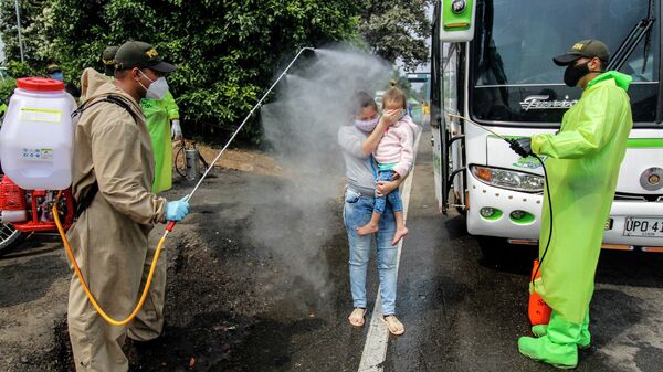 Сотрудники Национальной полиции проводят дезинфекцию граждан Венесуэлы, возвращающихся в страну из Колумбии, в качестве превентивной меры против распространения коронавируса