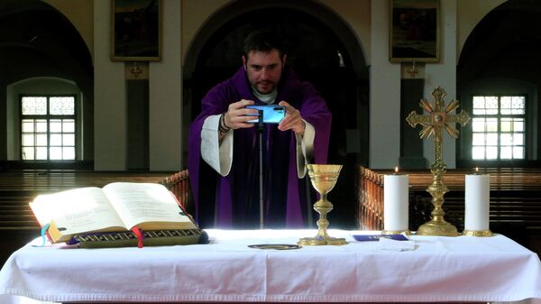 Священник ведет трансляцию в церкви в Бохиню, Словения
