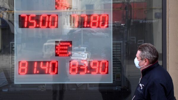 Мужчина в медицинской маске у информационного табло с курсом валют на улице Земляной Вал