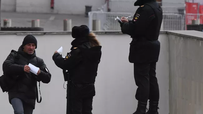Сотрудники полиции проверяет документы у мужчины в Москве