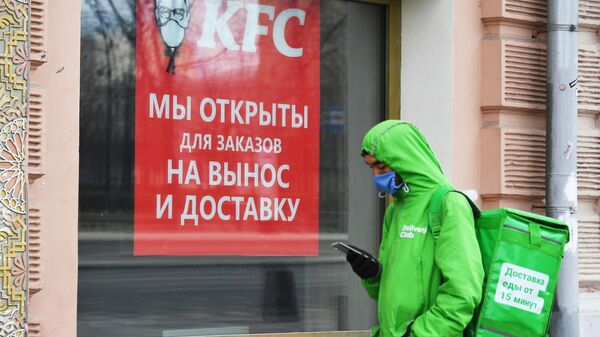 Курьер службы доставки еды Delivery Club стоит в очереди у окна кафе KFC