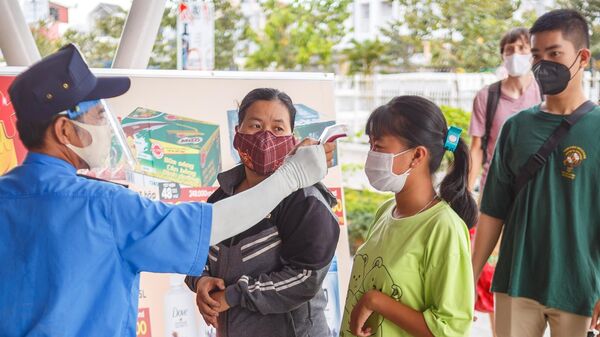 Охранник измеряет температуру у покупателя на входе в супермаркет в курортном городе Нячанг во Вьетнаме