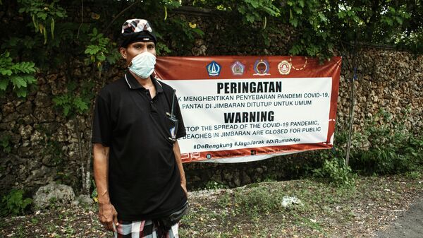 Местный житель в защитной маске в поселке Джимбаран на острове Бали в Индонезии