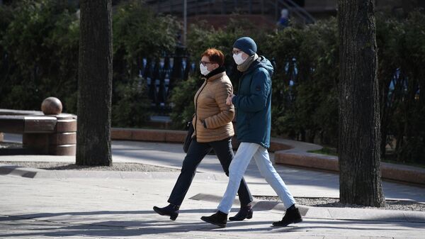 Жители Минска идут по улице в защитных масках