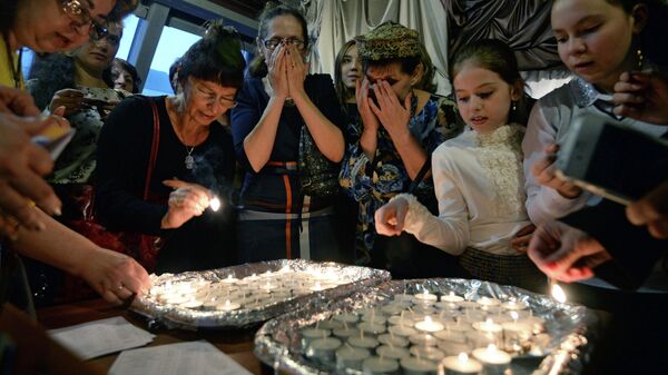 Женщины зажигают свечи в Новосибирском еврейском общинном культурном центре перед началом пасхального седера во время иудейского праздника Песах