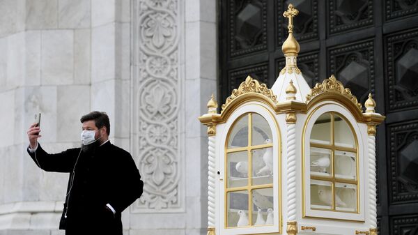 Священнослужитель в защитной маске после окончания Божественной литургии в храме Христа Спасителя в Москве