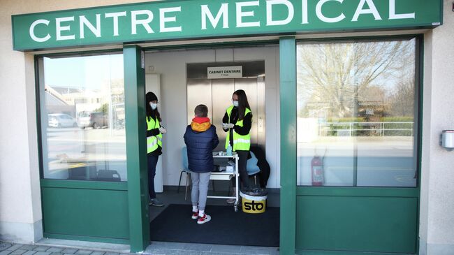 Волонтеры в защитных масках у входа в медицинский центр в Швейцарии