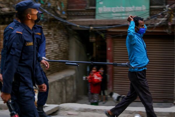 Полицейский во время задержания мужчины, нарушающего режим карантина, на одной из улиц Катманду, Непал