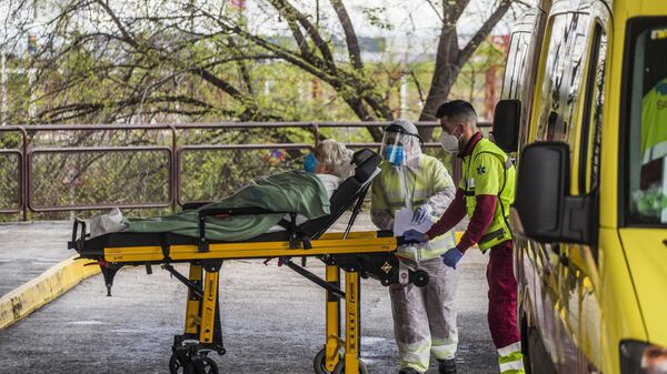 Медицинские работники доставляют пациента на каталке в приемное отделение госпиталя Северо Очоа в Мадриде