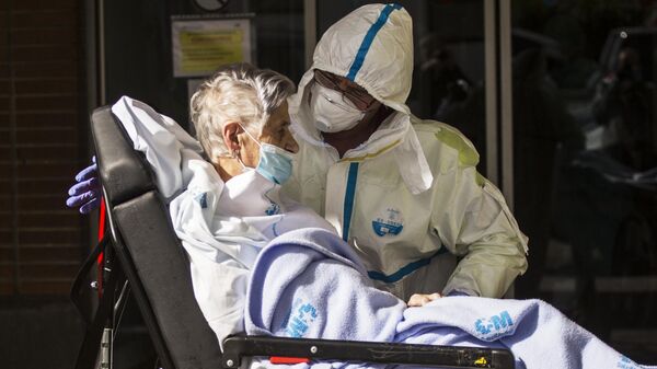 Медицинский работник доставляет пациента на каталке в приемное отделение госпиталя Северо Очоа в Мадриде