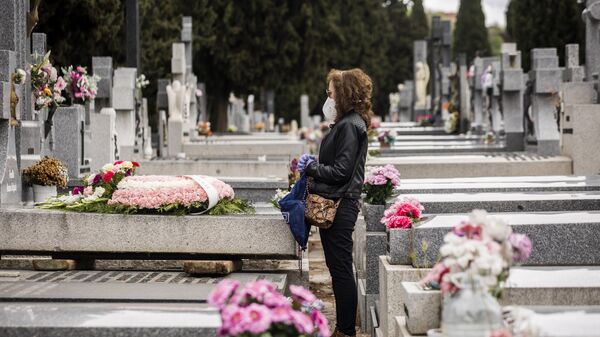 Женщина стоит у могилы матери, умершей от коронавируса, на кладбище Альмудена в Мадриде
