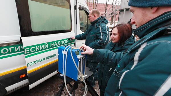 Сотрудники настраивают прибор для забора проб воздуха в Москве