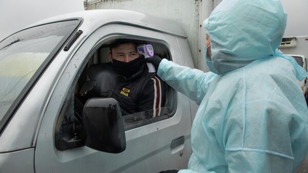 Медицинский работник проверяет температуру у водителя на блокпосте при въезде в Алма-Ату