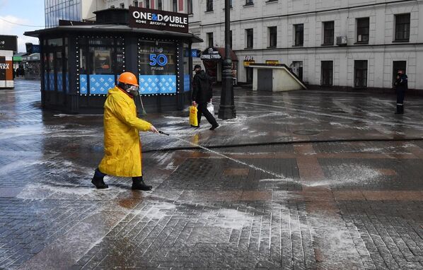 Сотрудник коммунальной службы проводит дезинфекцию тротуара у выхода со станции метро Комсомольская в Москве