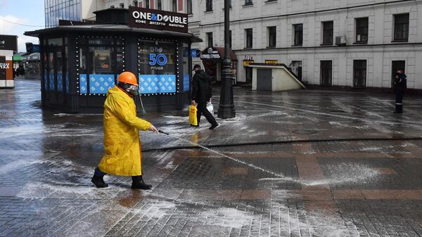 Сотрудник коммунальной службы проводит дезинфекцию тротуара у выхода со станции метро Комсомольская в Москве