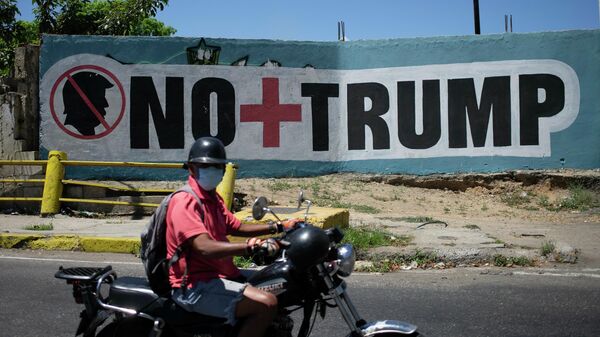Мужчина в защитной маске проезжает мимо граффити в Каракасе