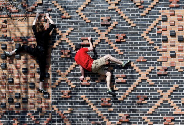 Альпинисты тренируются на стене дома в районе Хафенсити в Гамбурге, Германия