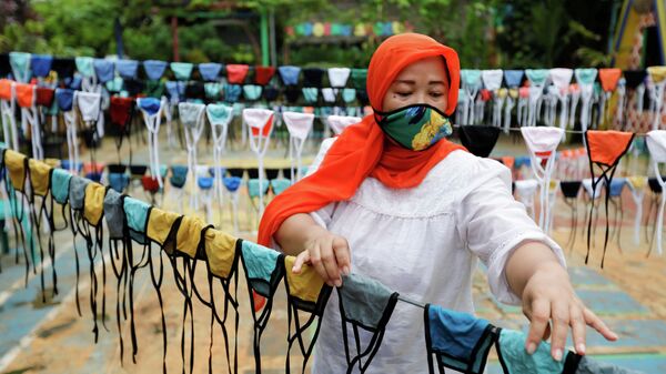 Женщина сушит тканевые маски для лица, прежде чем раздать их бесплатно по окрестностям в Тангеранге, на окраине Джакарты, Индонезия