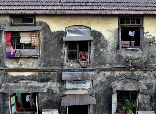 Мужчина в окне дома во время карантина в Мумбаи