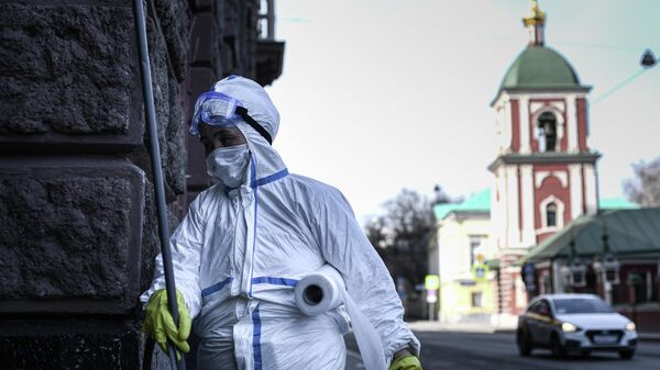 Сотрудник коммунальной службы в защитном костюме во время работы в центре Москвы