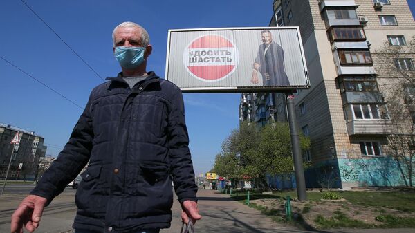 Мужчика в защитной маске у рекламного щита, установленного в Киеве в связи с коронавирусом