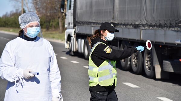 Медицинский работник и сотрудник правоохранительных органов Украины проверяют водителей на блокпосте во Львовской области