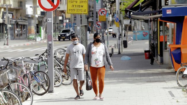 Прохожие в медицинских масках на одной из улиц Тель-Авива