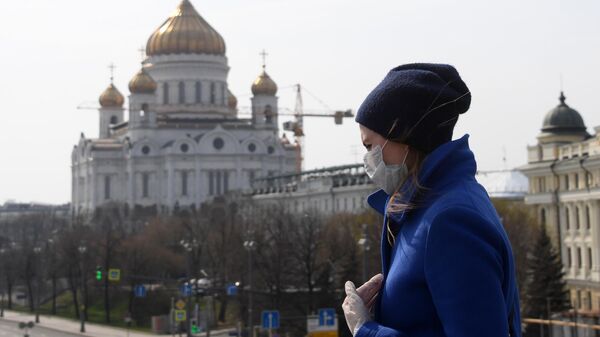 Девушка в защитной маске и перчатках на фоне Храма Христа Спасителя, закрытого для посещения