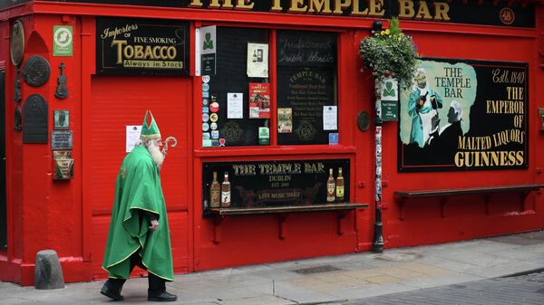 Мужчина в костюме Святого Патрика проходит мимо паба в Дублине 
